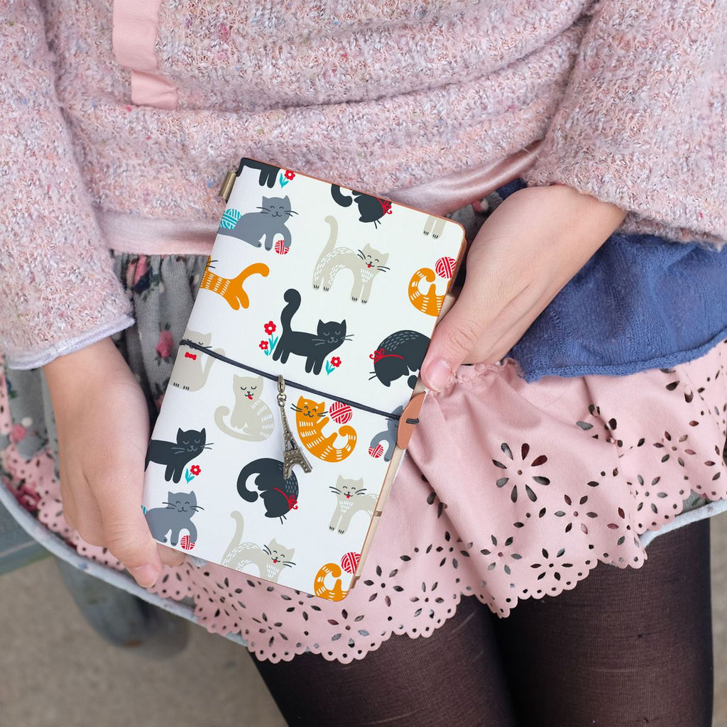 
a young girl showing midori style traveler's notebook with playful pussycats design above her leg