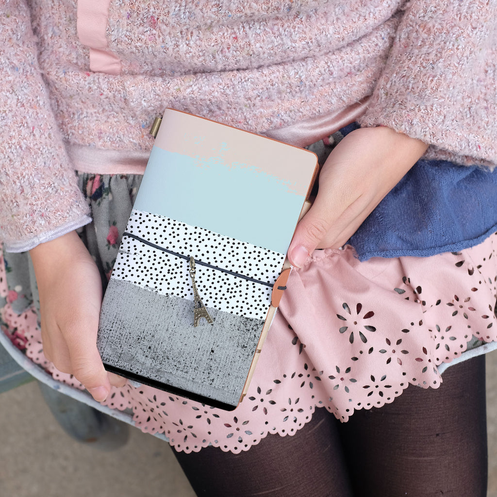 
a young girl showing midori style traveler's notebook with scandi spots and stripes design above her leg